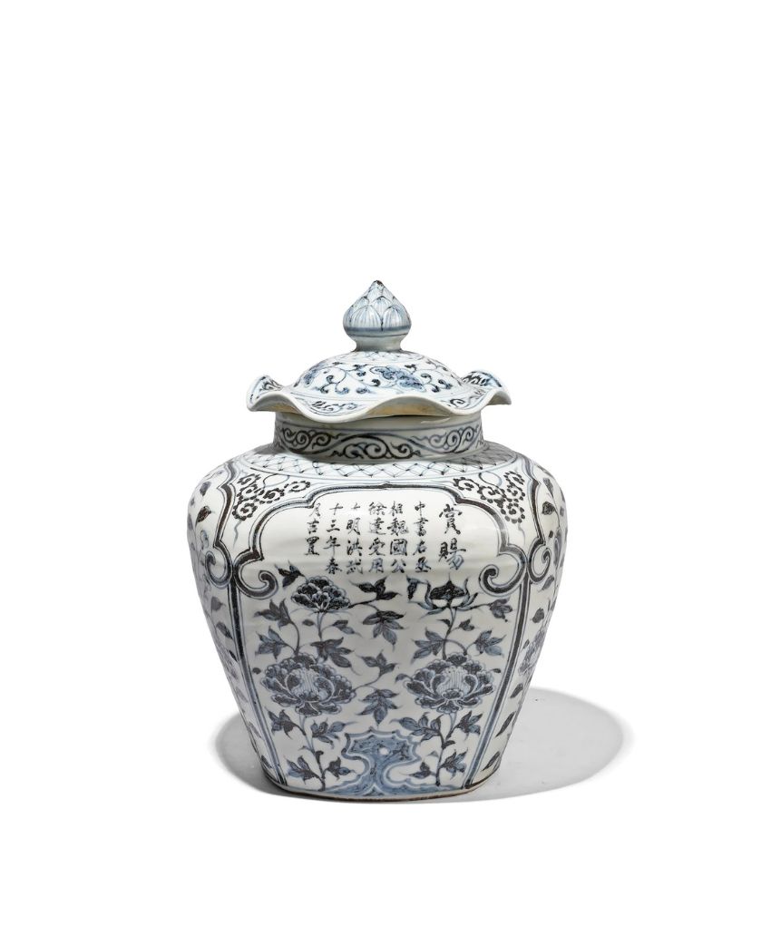A blue and white porcelain jar with a lid, decorated with intricate floral patterns and Chinese calligraphy. The jar features curved handles and traditional motifs, displayed against a plain white background.