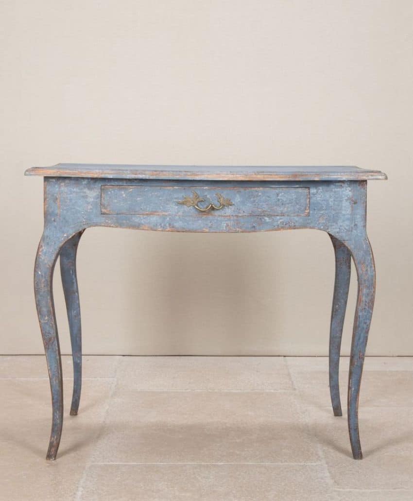 A vintage, distressed blue console table with curved legs and a single central drawer, set against a neutral background.