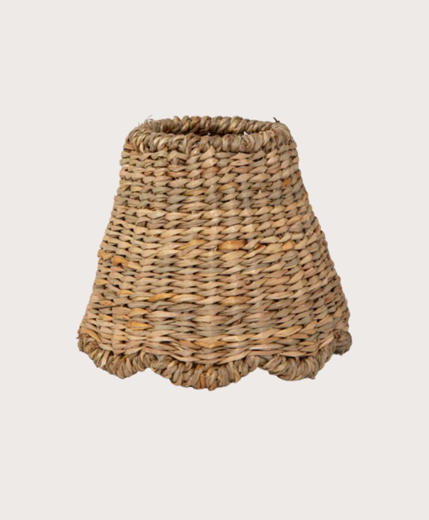 A woven, natural-colored wicker lampshade with a flared, scalloped bottom edge, set against a plain light background.