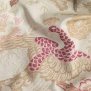 A close-up of fabric with a decorative pattern featuring a pink and beige peacock surrounded by floral designs on a light background.