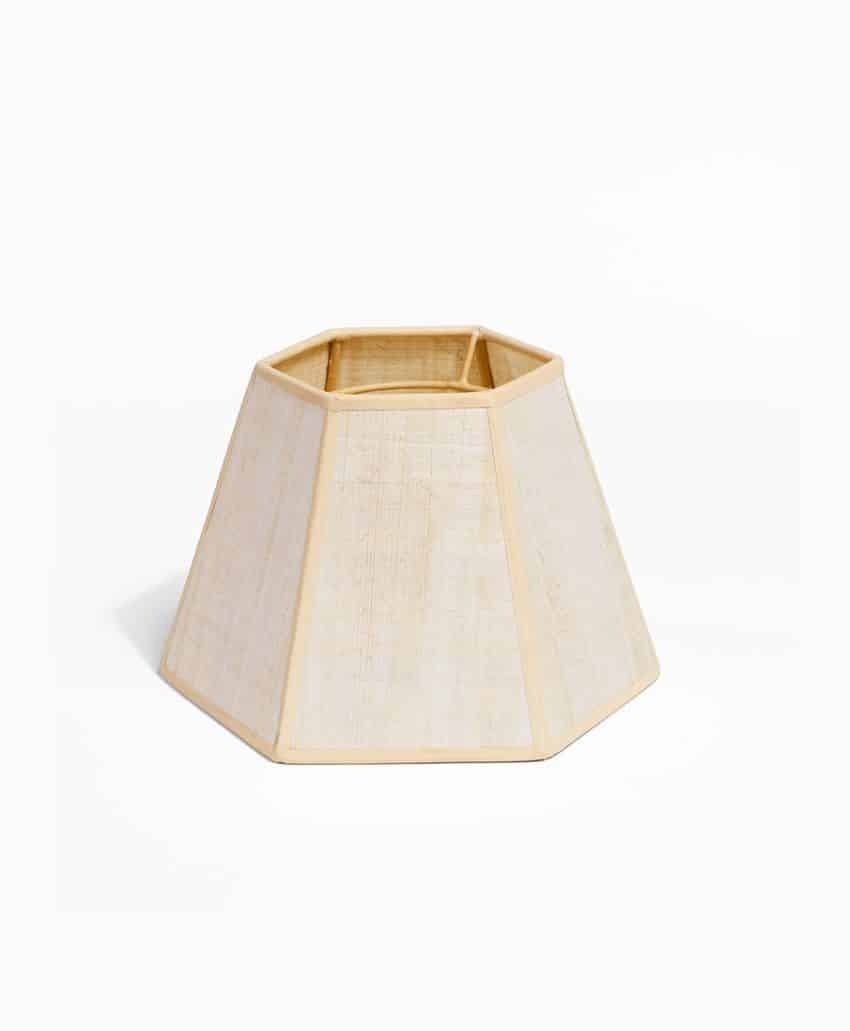 A light-colored, hexagonal lampshade with a slightly flared base and a woven texture, set against a plain white background.