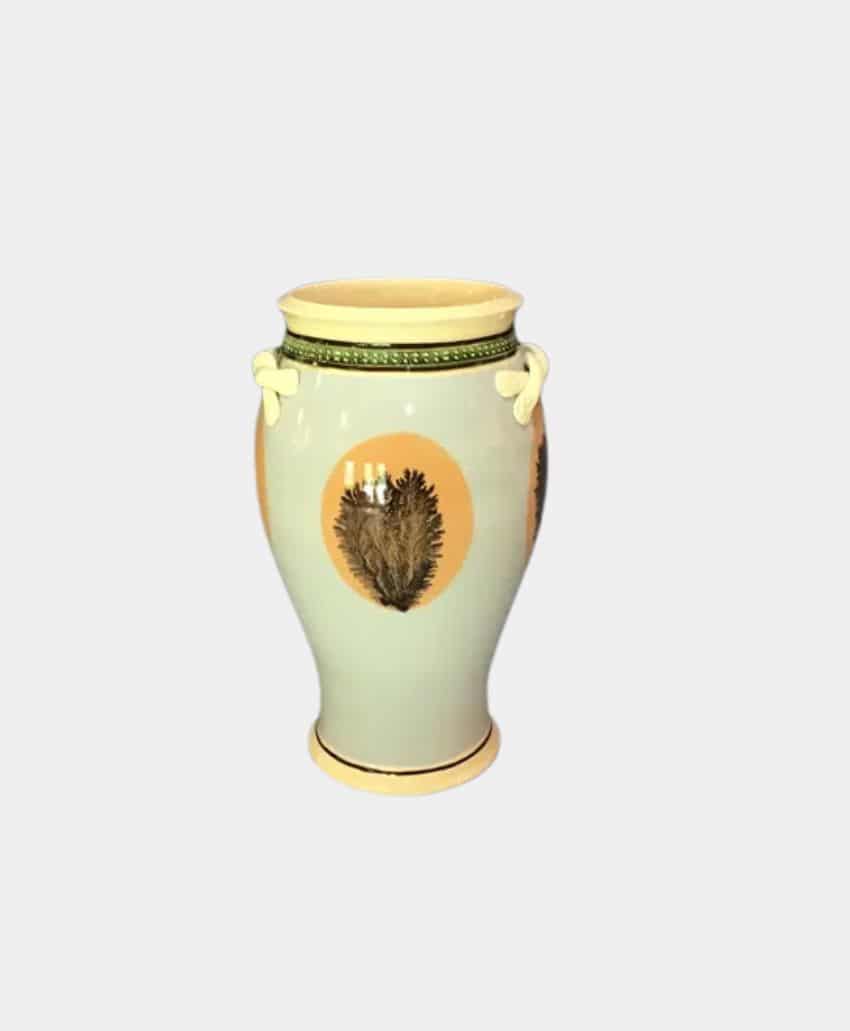 A cream-colored ceramic vase with yellow accents, green decorative trim near the top, and painted brown botanical designs on its sides, displayed against a plain light gray background.