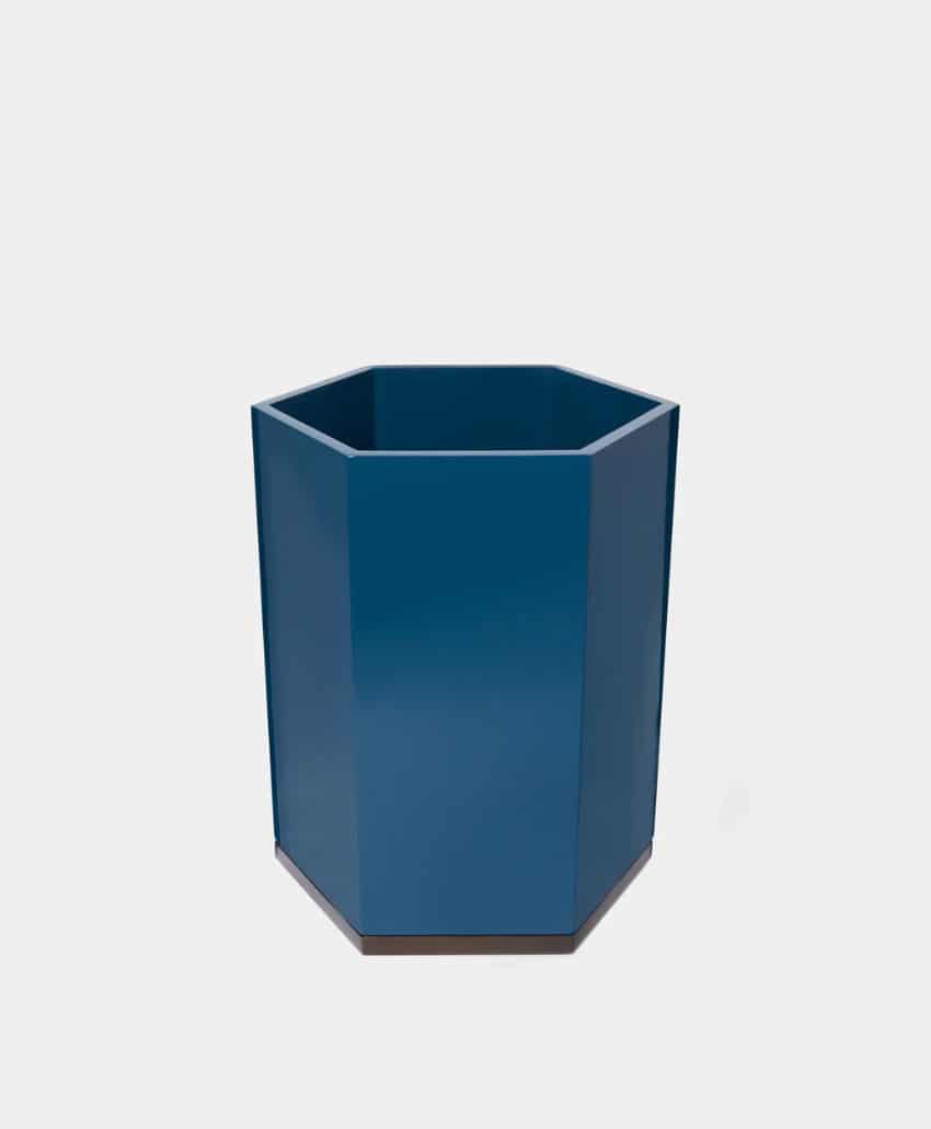 A blue, hexagonal container or planter with a matte finish, placed on a plain light gray background.