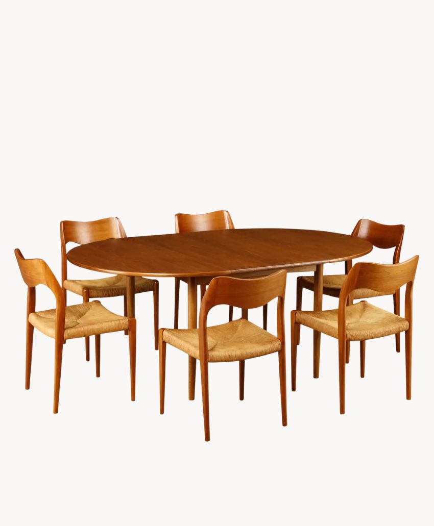 A mid-century modern dining set featuring an oval wooden table and six matching wooden chairs with woven seats, all set against a plain white background.
