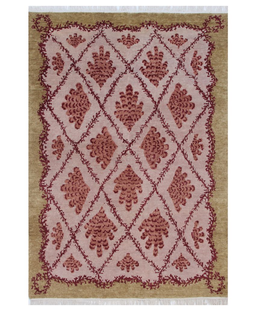 A rectangular area rug with a central pink field featuring red, symmetrical floral and diamond-shaped patterns, bordered by an olive green edge and finished with short white fringe on the ends.