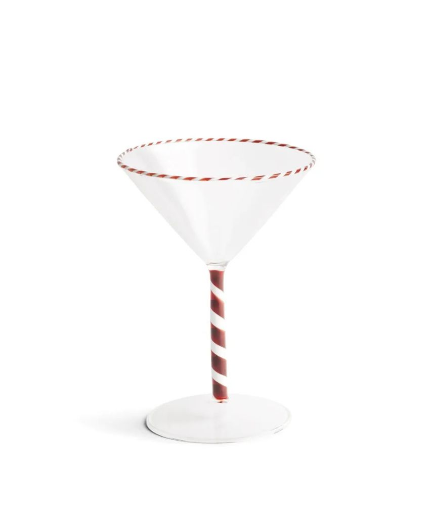 A clear martini glass with a red and white striped rim and a matching red and white spiral stem, set against a plain white background.