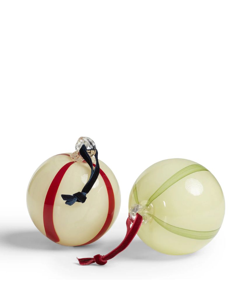 Two glossy, round ornaments with ribbon loops for hanging. One ornament has red stripes and a navy ribbon, while the other has light green stripes with a red ribbon. Both are set against a white background.