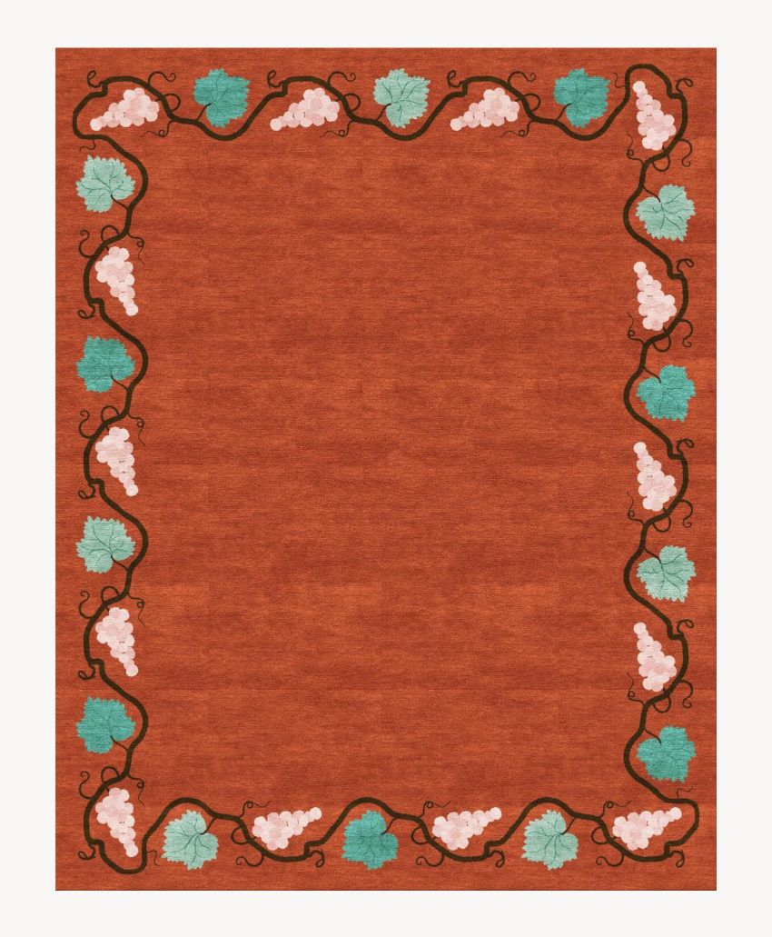 A reddish-brown rectangular rug with a border of grapevines, featuring clusters of pink grapes and green leaves, wrapping around the edges. The center is plain without any design.