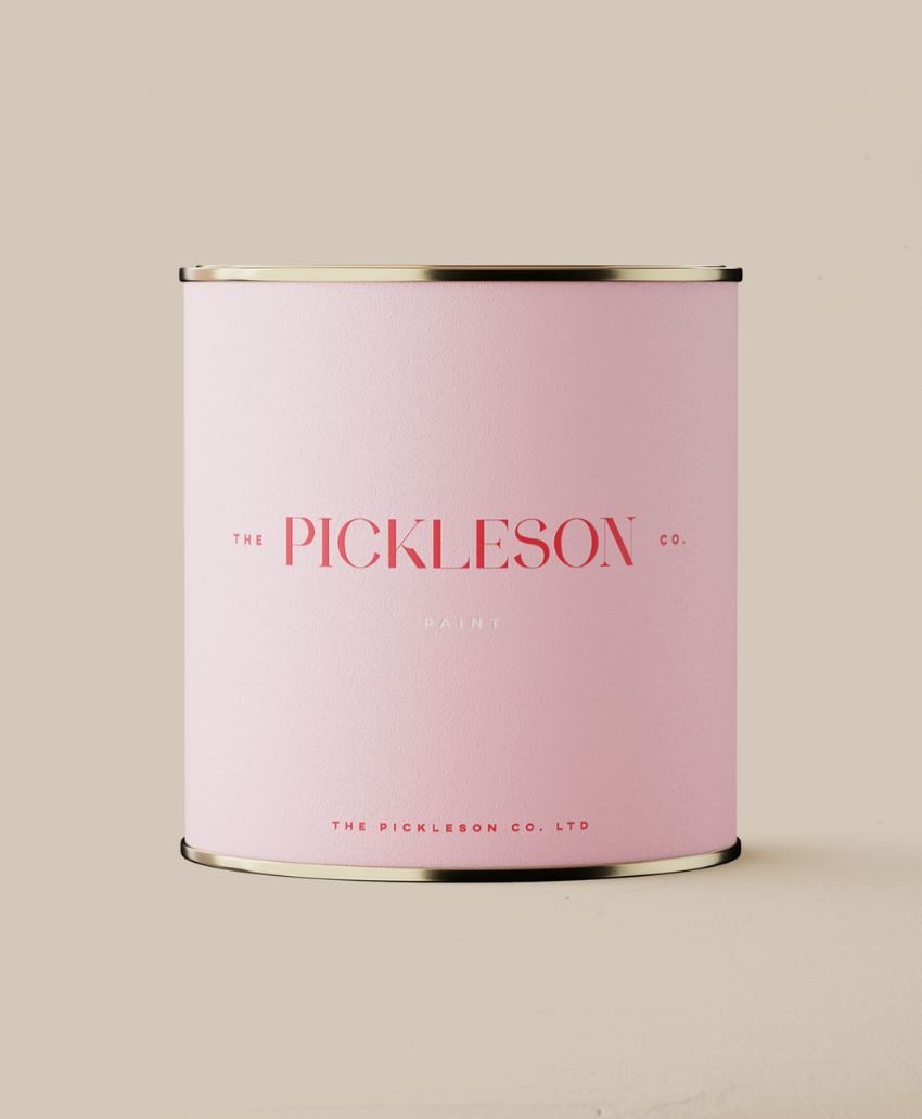 A light pink paint can with gold trim featuring minimalist text that reads The Pickleson Co. Paint in bold red letters on a plain beige background.