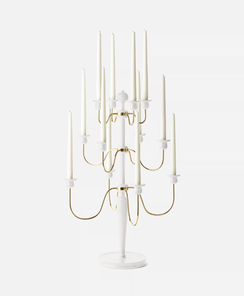 A modern candelabra with a white base and gold curved arms, holding ten tall, slender white candles arranged at varying heights.