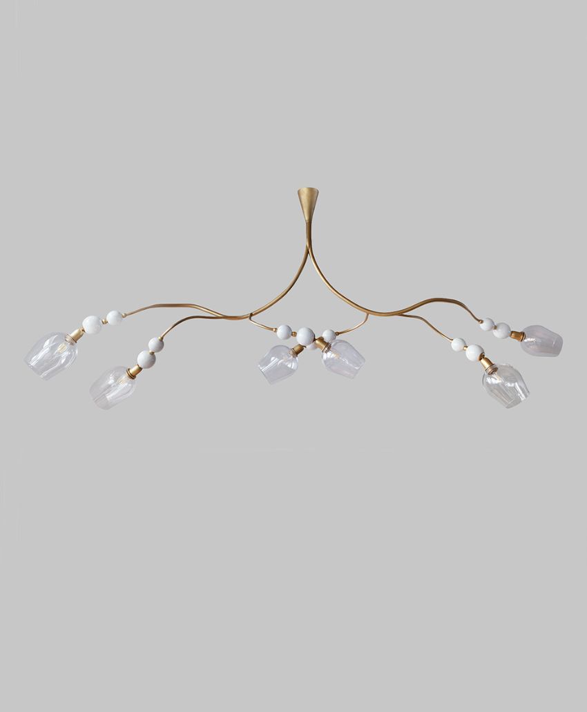 A modern chandelier with a gold metal frame, six curved arms, white spherical accents, and clear geometric glass shades, set against a plain light gray background.
