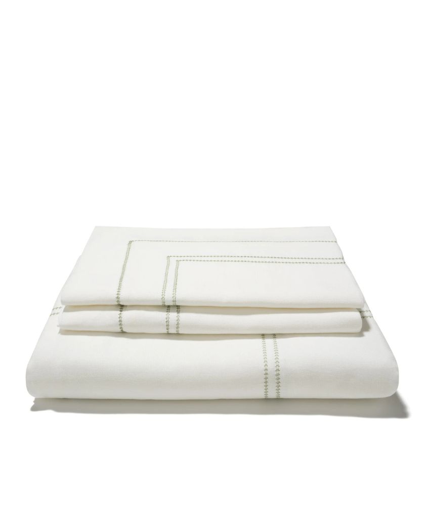 A neatly folded stack of white bed sheets with light green stitched detailing along the edges, set against a plain white background.