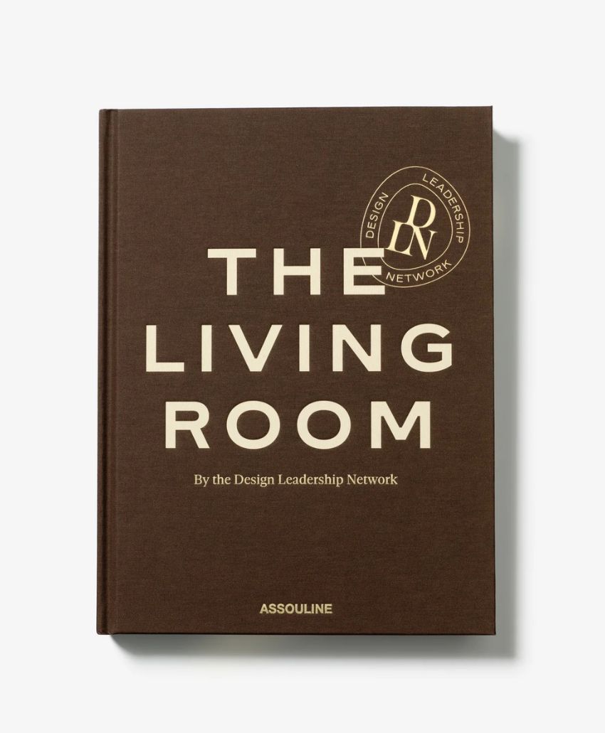 A brown hardcover book titled The Living Room by the Design Leadership Network is shown standing upright. The publishers name, Assouline, appears at the bottom.