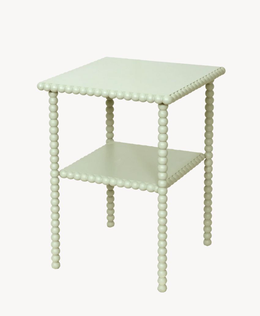 A light green square side table with a decorative beaded design on the edges and legs, featuring a lower shelf for additional storage.