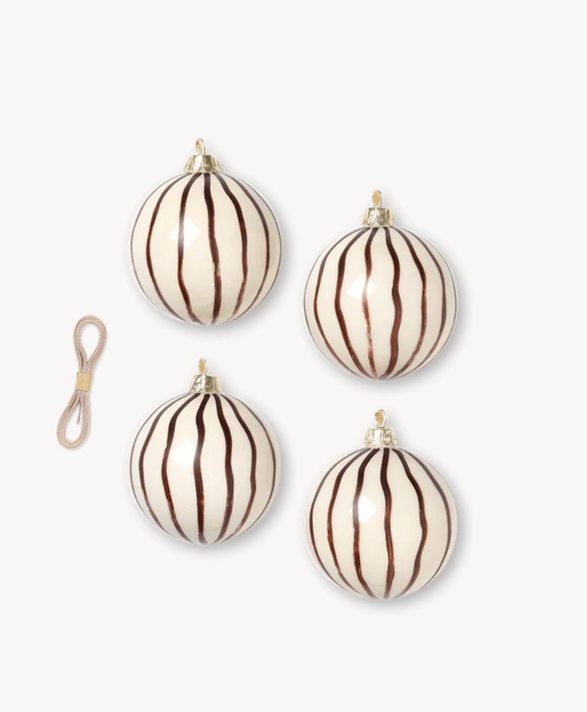 Four round white Christmas ornaments with vertical dark brown stripes are arranged in a grid pattern. A loop of light-colored string for hanging is placed to the left of the ornaments on a plain white background.