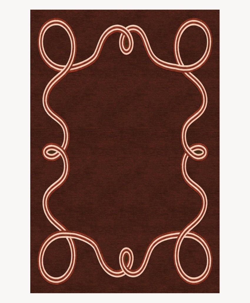 A rectangular dark brown rug features a looping, peach-colored border design that forms symmetrical, flowing curves on all sides, creating an elegant frame-like pattern.