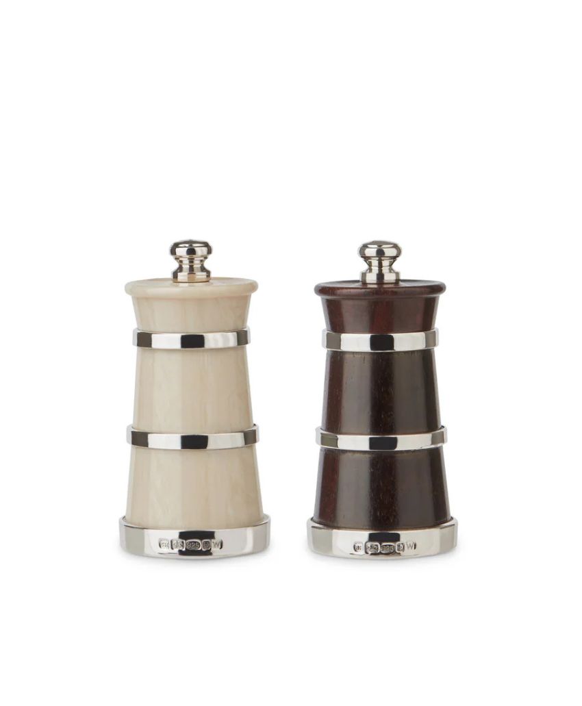 Two cylindrical salt and pepper mills, one white and one dark brown, with silver bands and knobs, standing side by side on a white background.