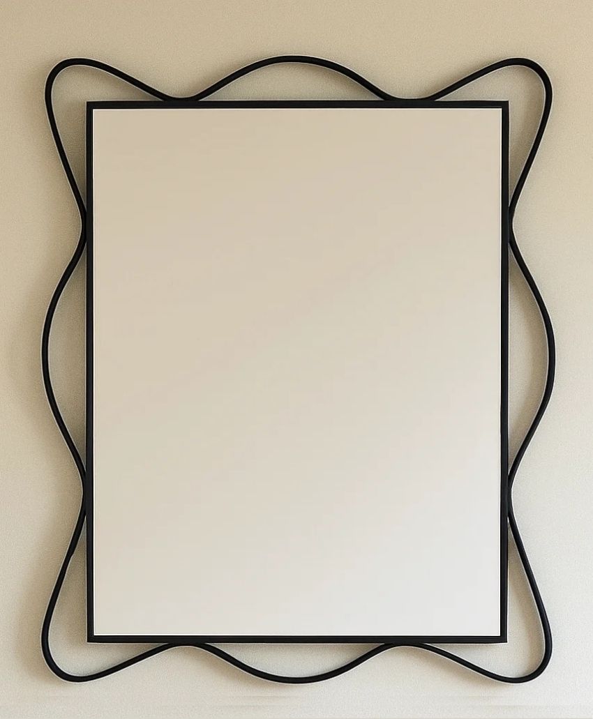 A rectangular mirror with a simple black frame, surrounded by an outer black metal border forming smooth, wavy, abstract curves on a beige wall.