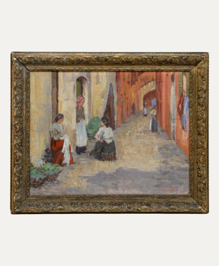 An impressionist painting in an ornate frame depicts women in traditional clothing conversing and working along a narrow, sunlit street lined with yellow and red buildings.