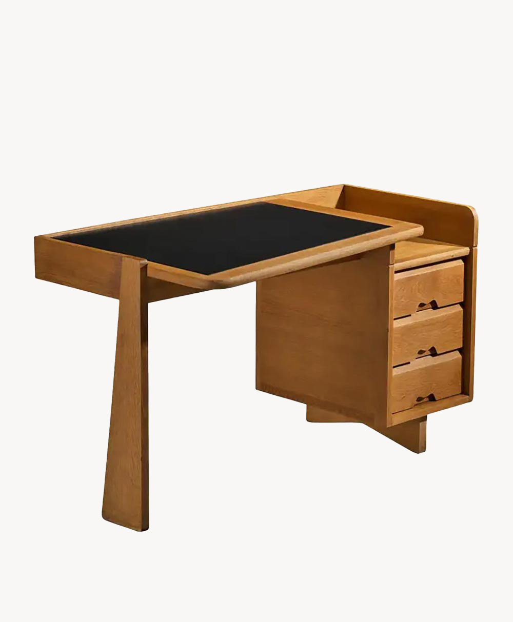 A modern wooden desk with a black tabletop, featuring three drawers on the right side and an asymmetrical leg design on the left.
