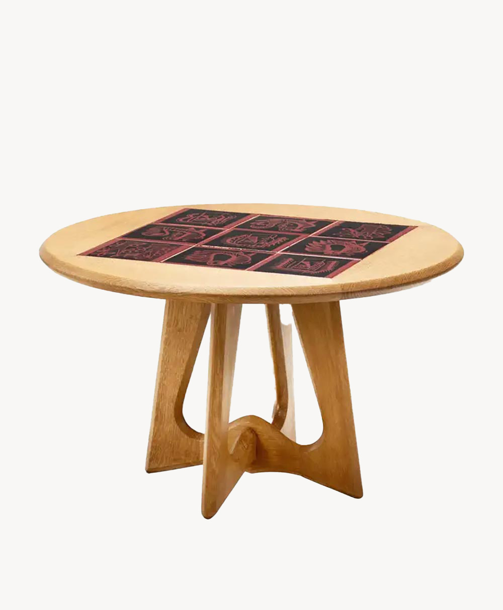 Round wooden table with a unique geometric base and a decorative inlaid top featuring nine red and black patterned tiles arranged in a square pattern.