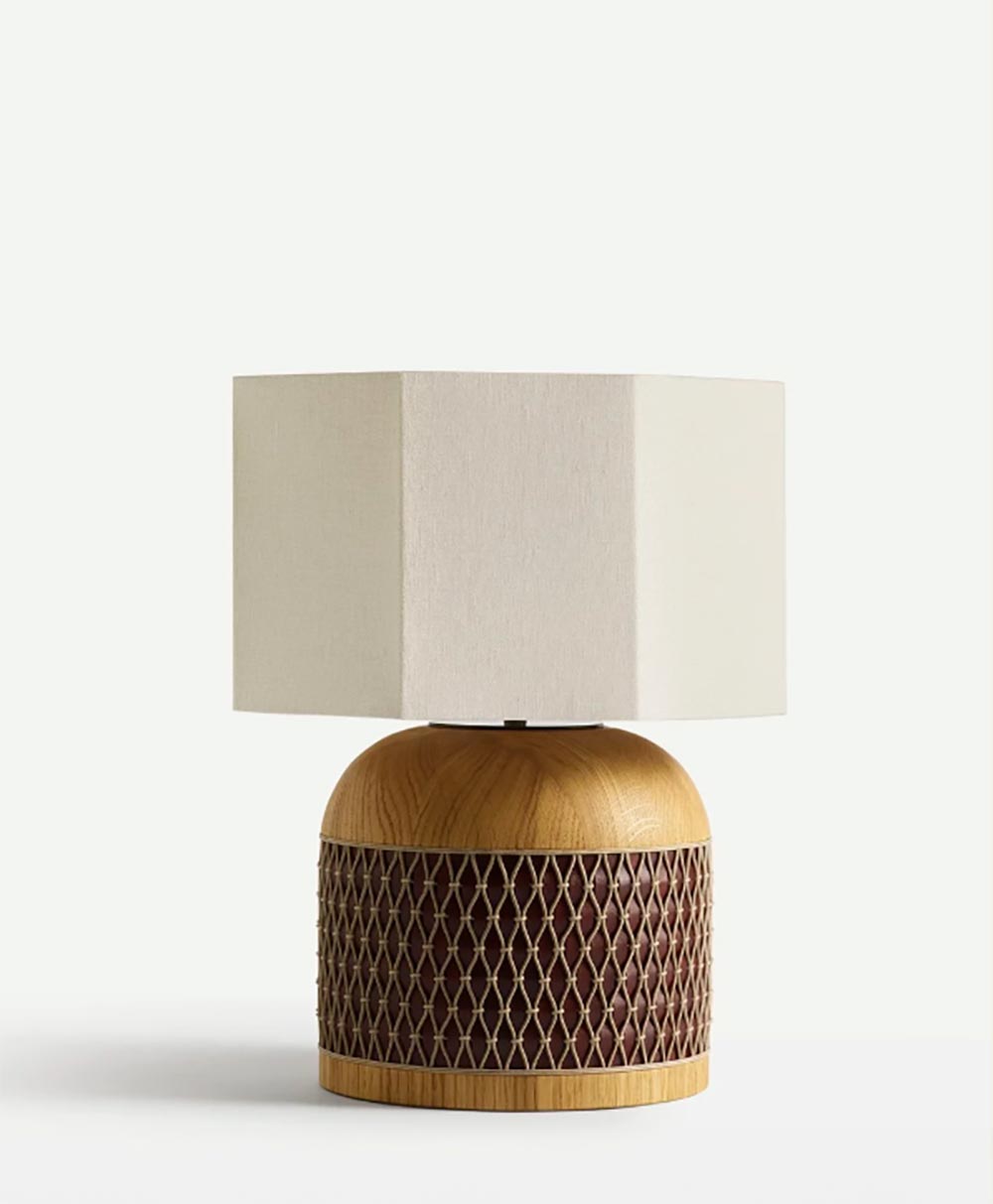 A table lamp with a square, off-white lampshade and a wooden, dome-shaped base featuring a lattice design and a smooth top and bottom.