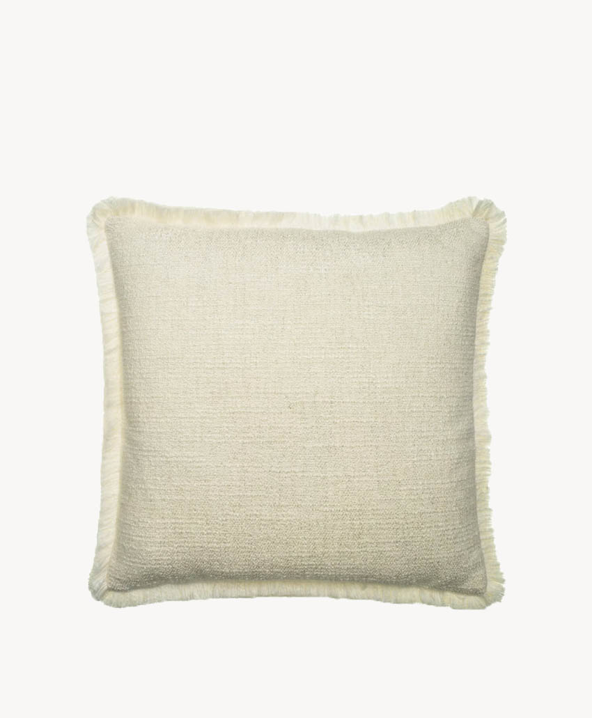 A rectangular, beige throw pillow with a soft, textured fabric and subtle fringe trim around the edges, displayed against a plain white background.