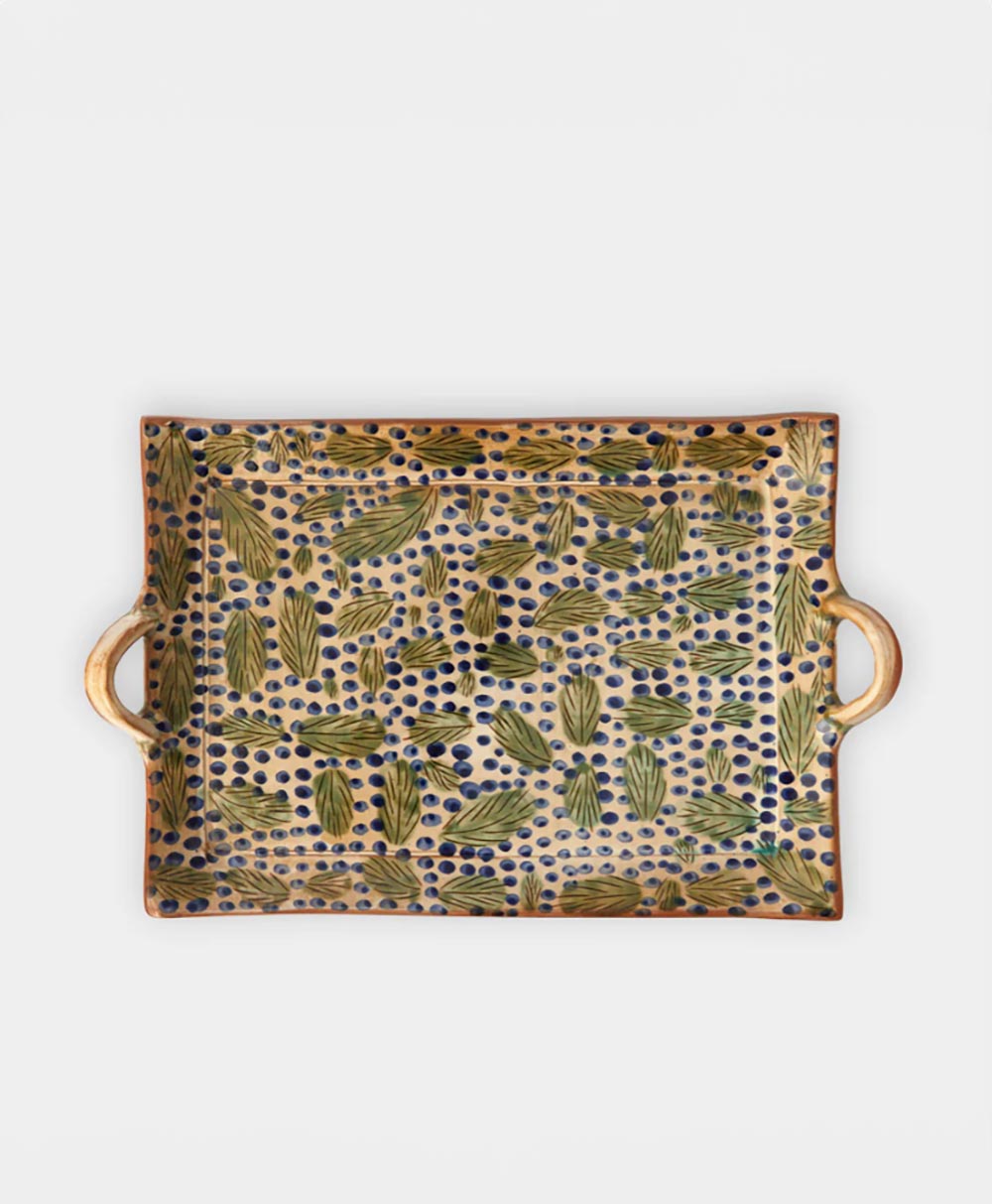 Rectangular ceramic tray with side handles, decorated with a pattern of green leaves and dark blue dots on a beige background.