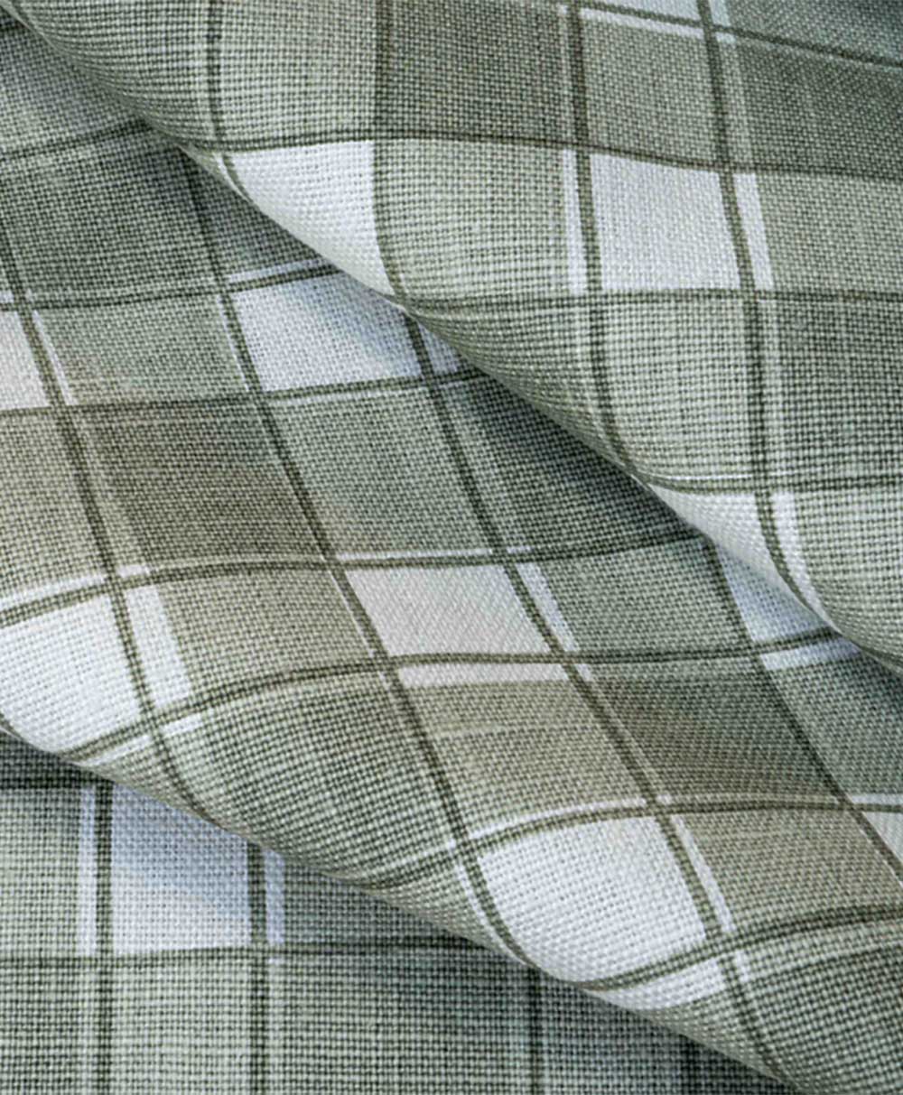 A close-up of folded fabric with a green and white plaid pattern featuring intersecting lines forming squares. The fabric texture is visible, and the folds add depth to the image.