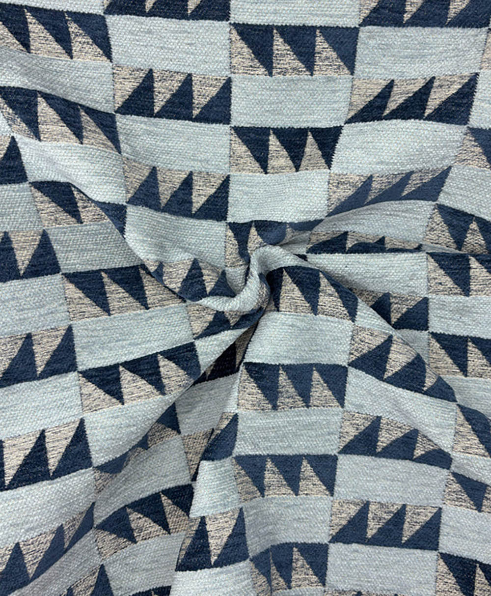A close-up of fabric featuring a geometric pattern with alternating rows of navy and light gray triangles. The fabric is twisted, creating folds and texture in the center.