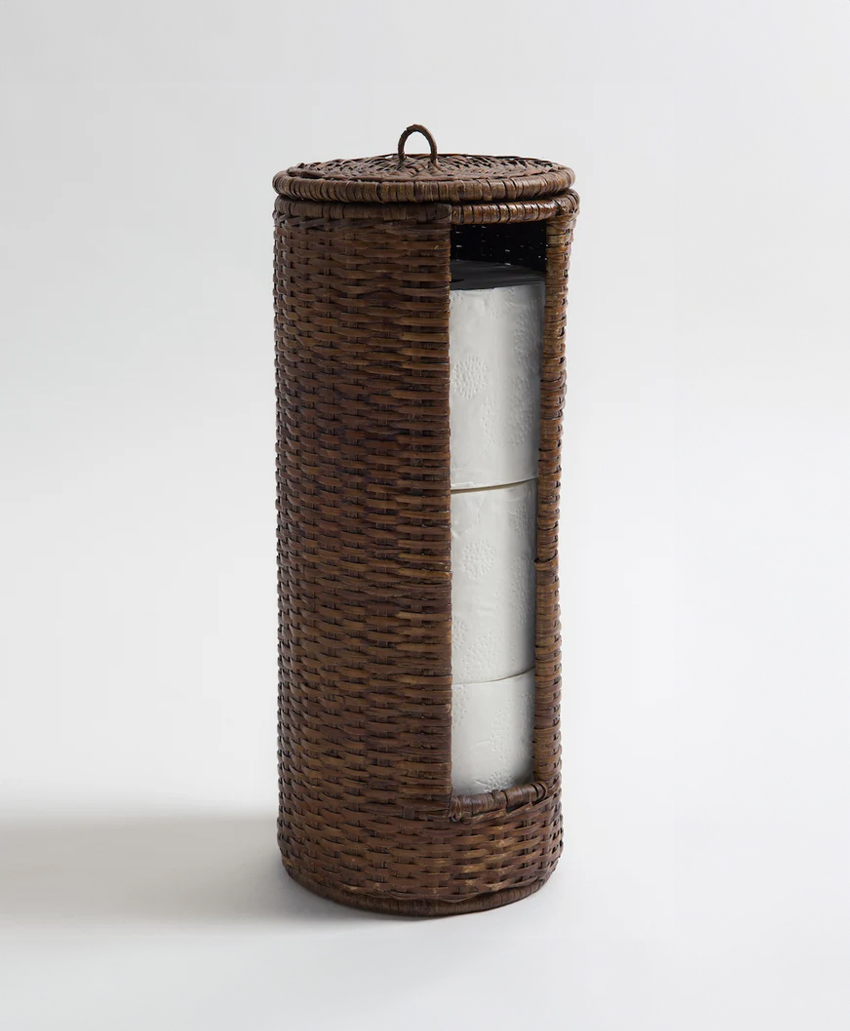 A cylindrical brown wicker holder with a lid, containing three visible rolls of white toilet paper stacked vertically inside.