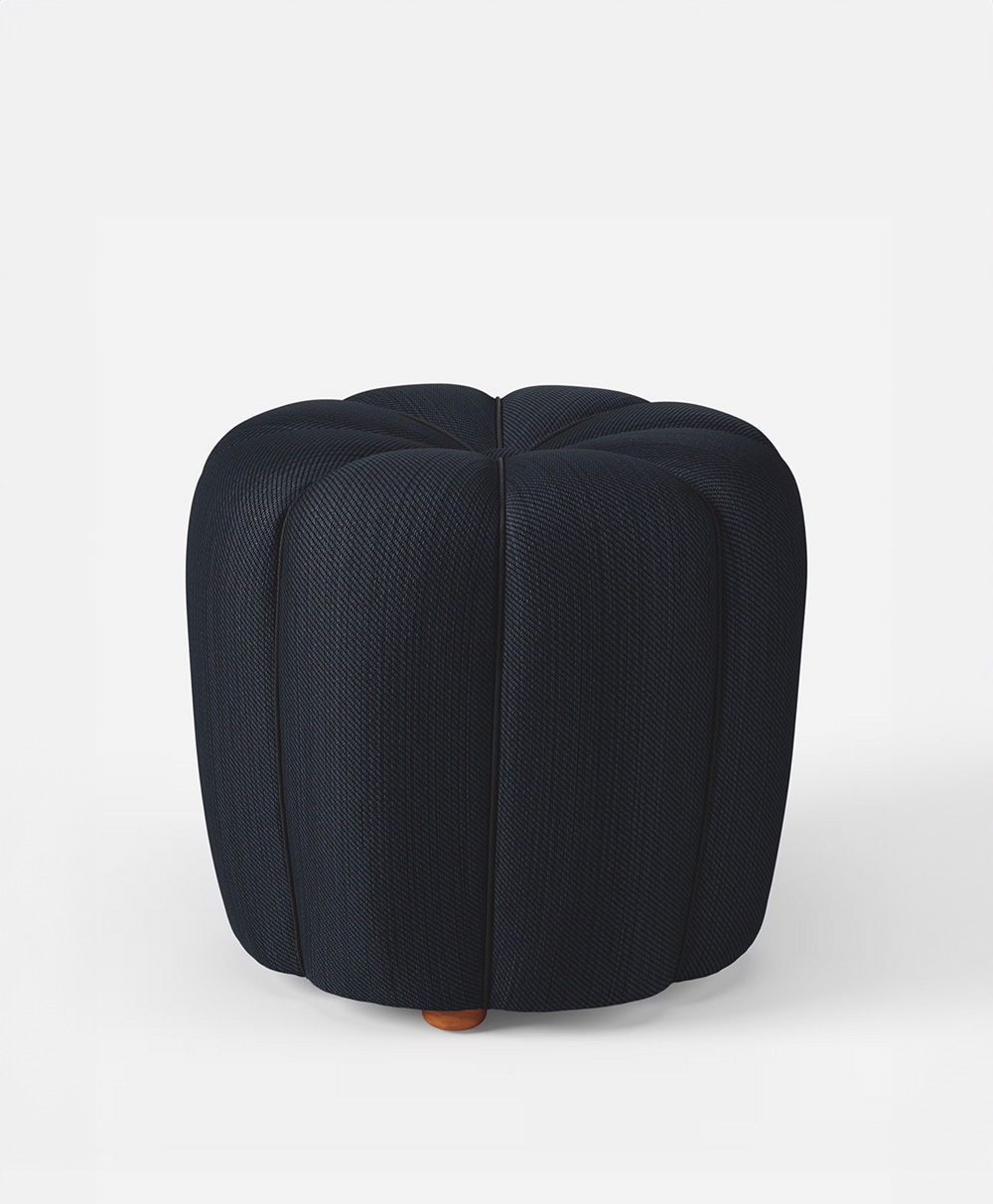 A dark blue, round, upholstered ottoman with subtle vertical stitching and a slightly textured fabric, placed on a light background.