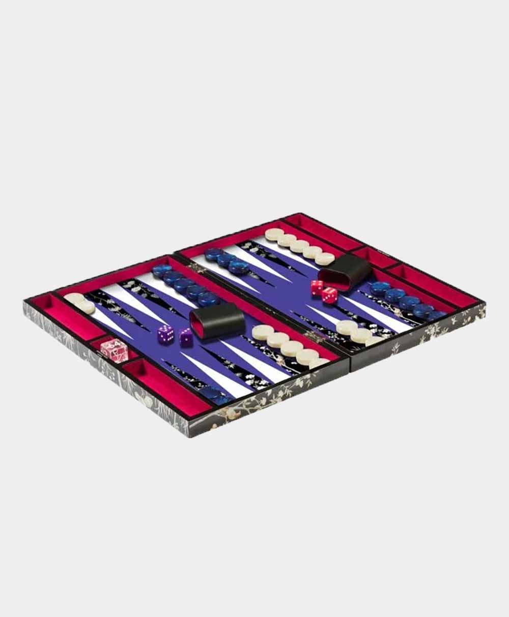 A backgammon board with a purple playing surface, red borders, and black, white, and blue checkers arranged for play. There are two black dice cups and several dice on the board.