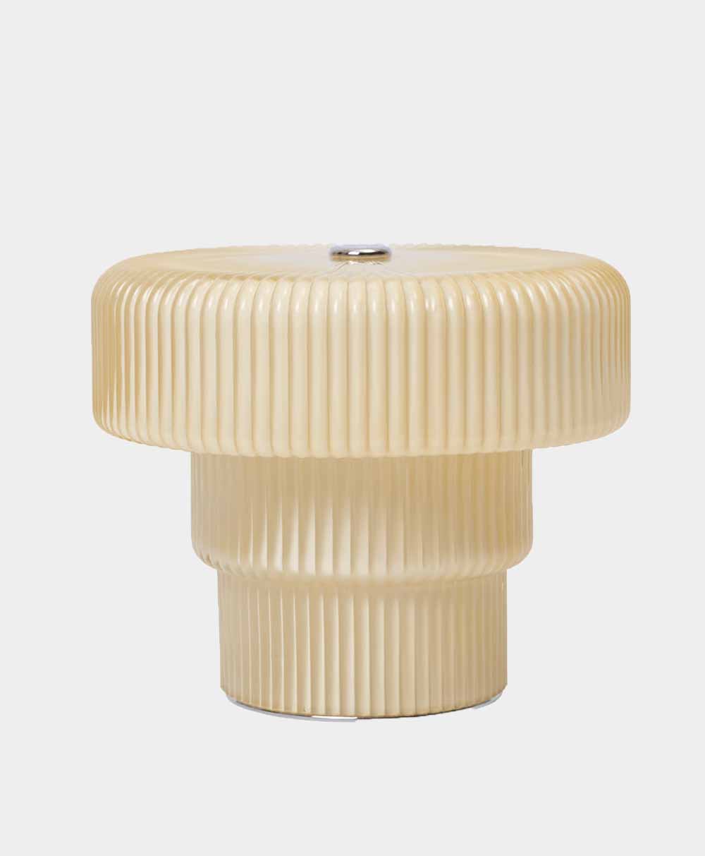 A beige, ribbed, mushroom-shaped object with a metallic button on top, set against a plain light gray background.