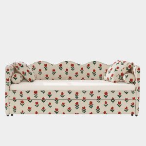 A cream-colored daybed with a wavy backrest, two matching pillows, and a red and green tulip floral pattern covering the entire surface, set against a plain white background.