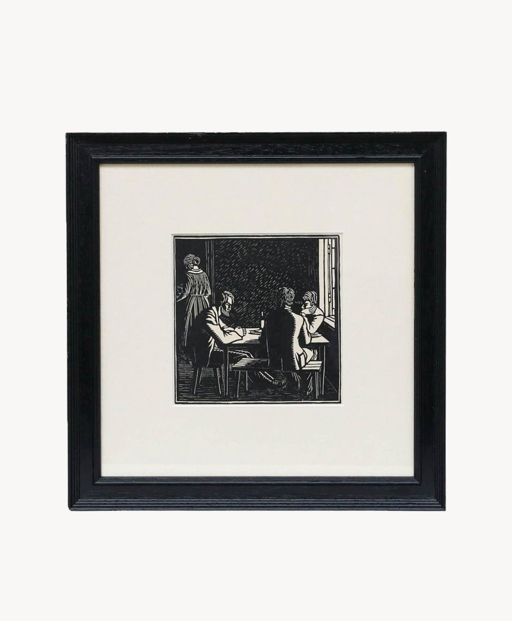 Black-and-white framed artwork showing three people seated around a table and one standing in the background. The scene appears indoors, with simple, bold lines and contrasting shadows.