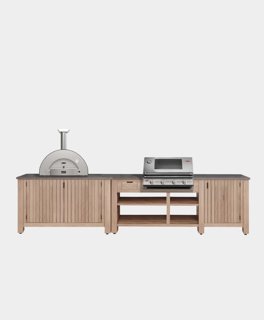 An outdoor kitchen unit featuring a wood-fired pizza oven on the left, a built-in stainless steel gas grill in the center, storage cabinets, drawers, and open shelves beneath a dark countertop.
