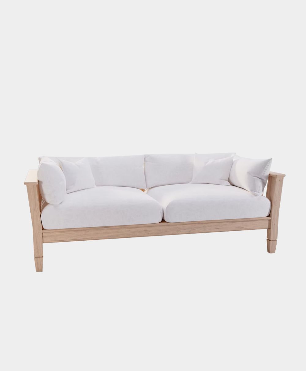 A modern sofa with a light wooden frame and white cushions, featuring two seat cushions, four back pillows, and two side pillows, against a plain white background.
