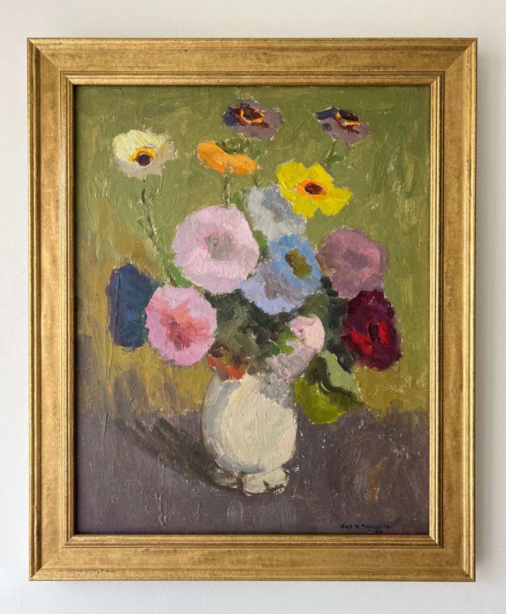 A framed painting of a vase with colorful flowers, including pink, yellow, purple, and red blooms, set against a green background. The artwork has a textured, impressionistic style.