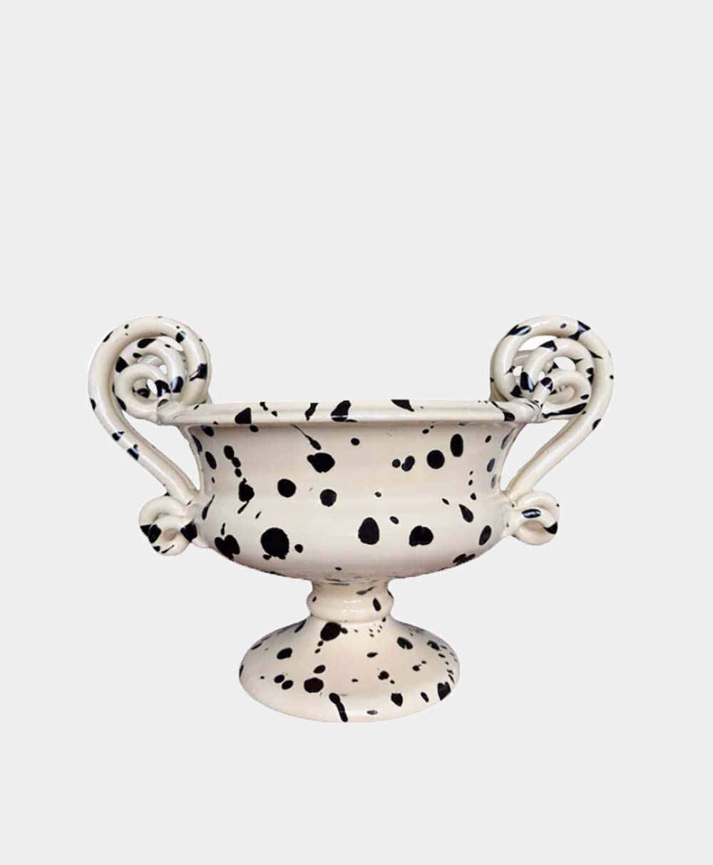 A decorative cream-colored ceramic vase with two ornate, curled handles, featuring a black splatter pattern throughout, set against a plain white background.