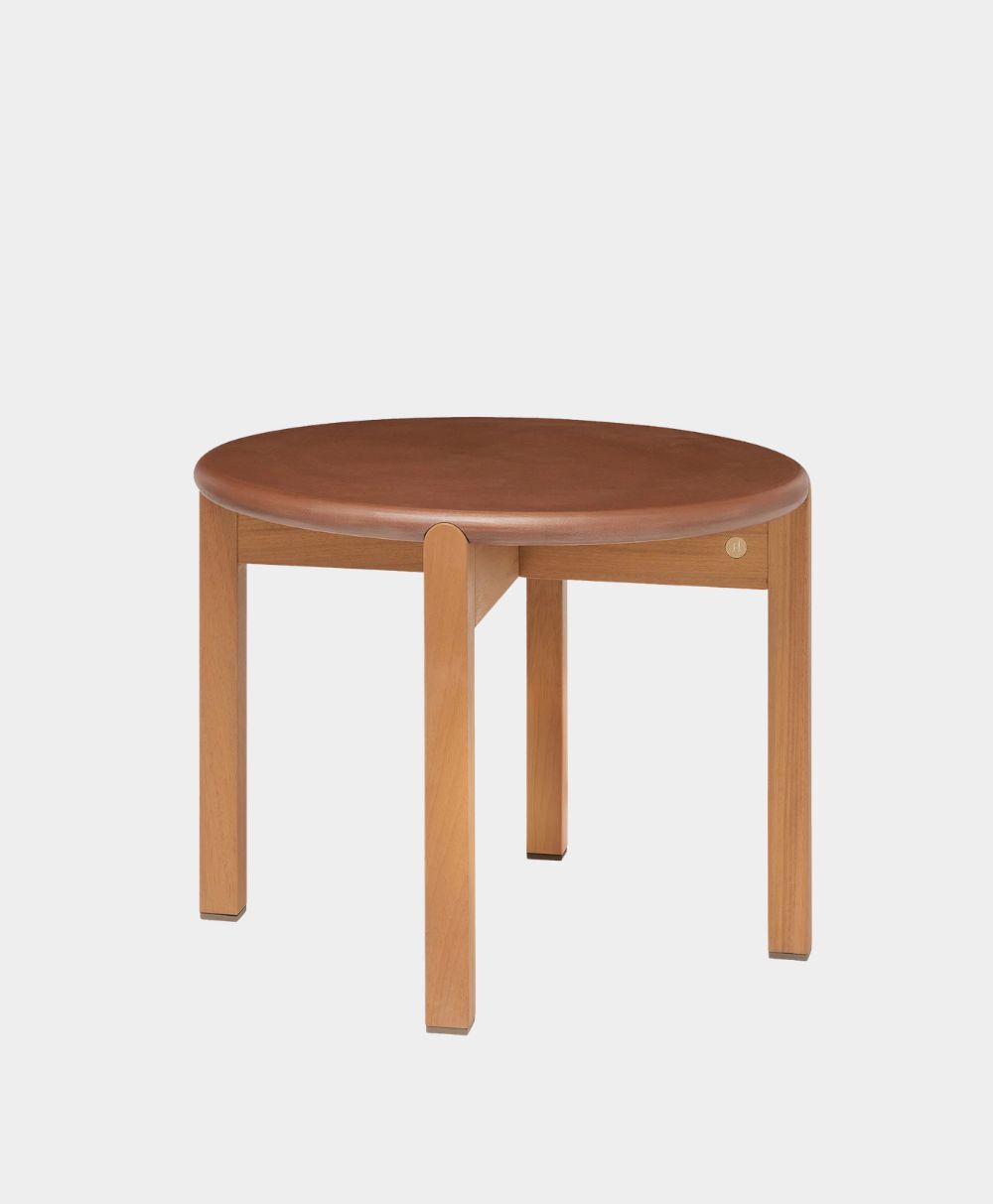 A round wooden table with a smooth top and four straight legs, set against a plain, light background. The table has a simple, modern design.