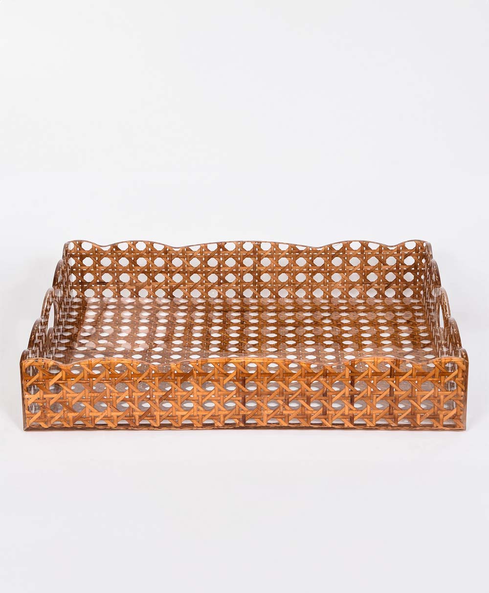 A rectangular woven rattan tray with cut-out circular and star patterns, scalloped edges, and handles on each end, set against a plain white background.