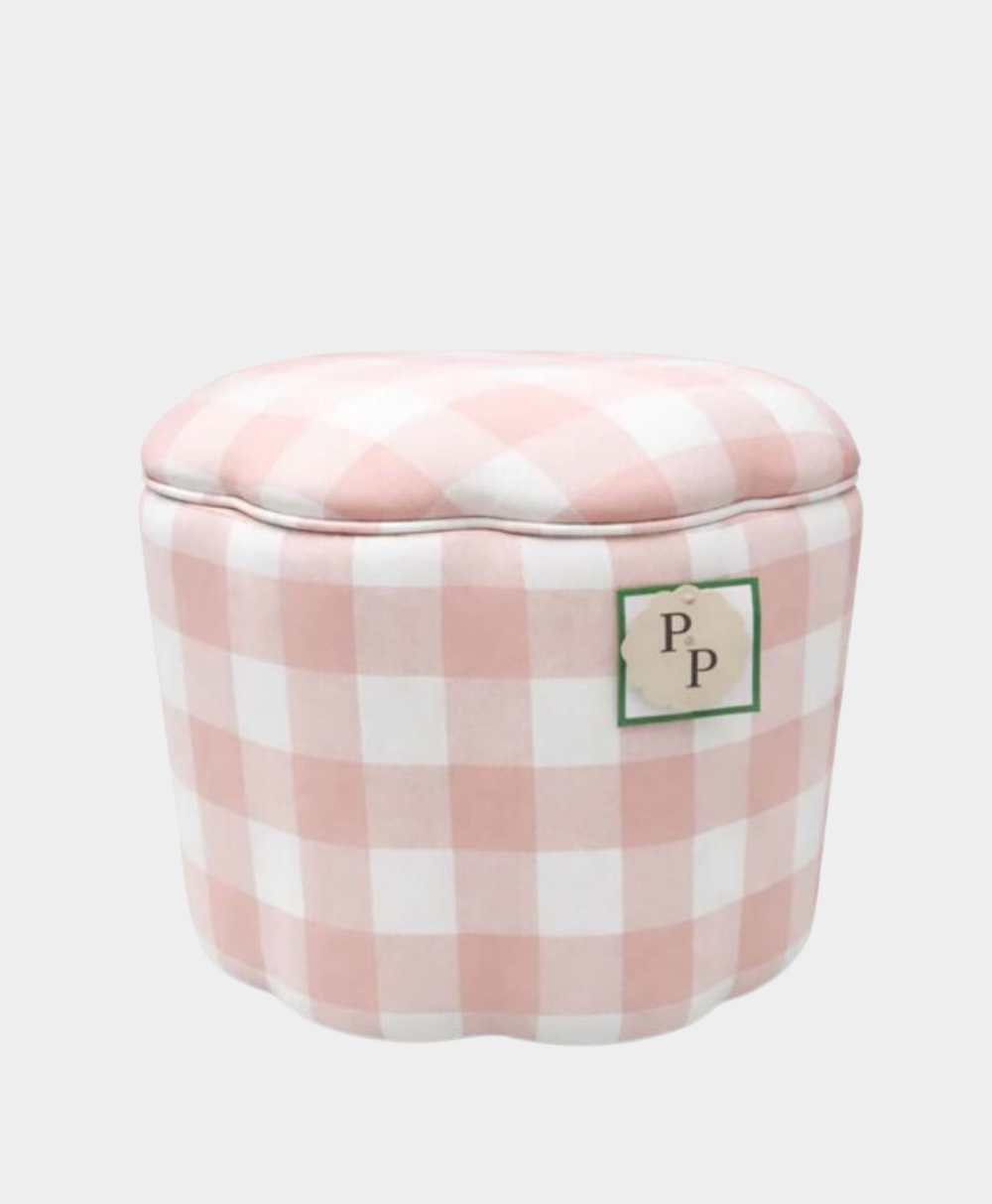 A small, round ottoman upholstered in pink and white gingham fabric, featuring a patch with the initials PP on the side.