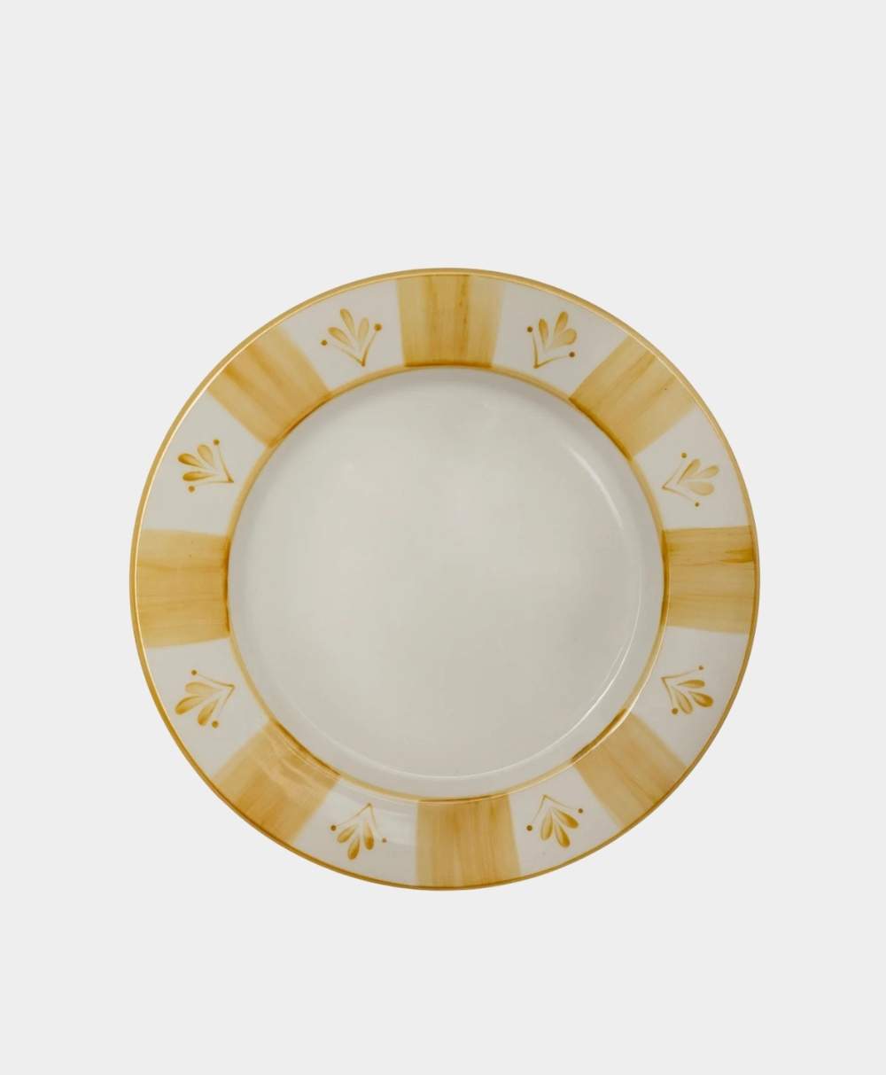 A white ceramic plate with a wide rim featuring alternating yellow and white segments, each white segment decorated with a small gold floral pattern.