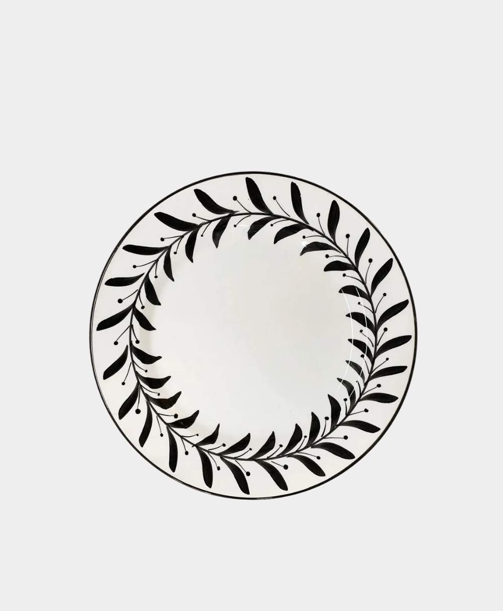 A white ceramic plate with a black leafy vine pattern circling the rim, viewed from above on a plain white background.