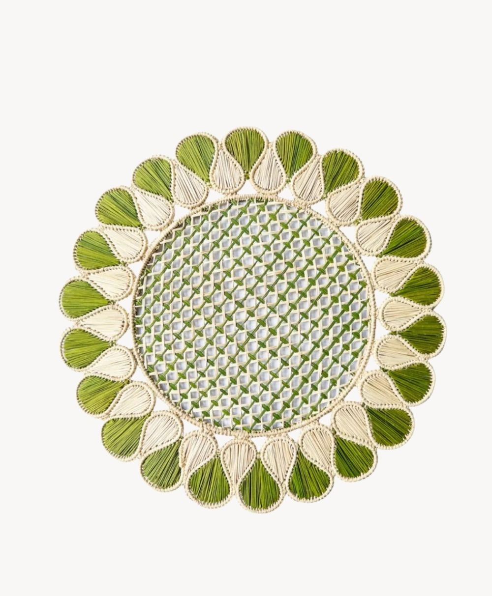 A round woven placemat with a green and cream geometric pattern in the center and a scalloped border featuring alternating green and cream teardrop shapes.