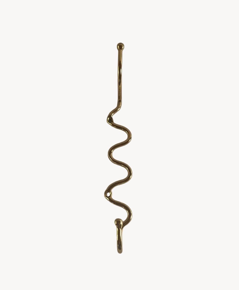 A brass wall hook with a wavy, zigzag design and two upward-facing hooks at the top and bottom, set against a plain white background.