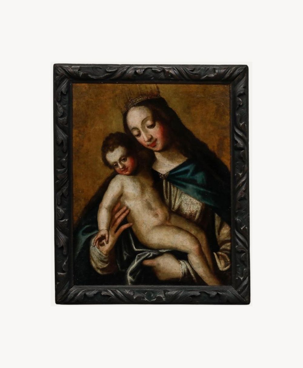 An oil painting in a dark, ornate frame depicts a crowned woman in a blue robe holding a naked child. The woman gazes gently at the child, who leans against her with one arm resting on her hand.