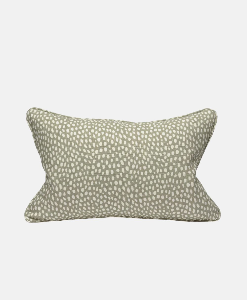Rectangular throw pillow with a light beige background and an irregular white dot pattern, resembling animal print, on a plain white surface.