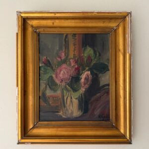 A framed painting of pink and red roses with green leaves in a vase, set against a dark background. The frame is gold with some visible wear and chipping along the edges.